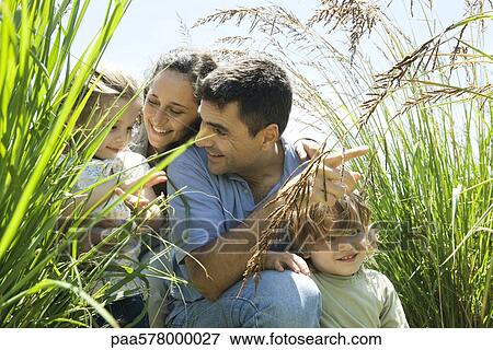 Family crouching together in tall grass View Large Photo Image Stock Photo - Family crouching together in tall grass. Fotosearch