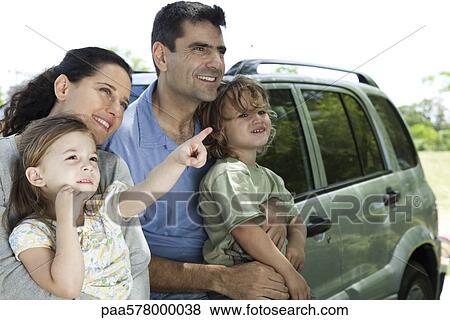 Family leaning against car, all looking as daughter points at something in distance View Large Photo Image Stock Photo - Family leaning against car, all looking as daughter points at something in distance. Fotosearch