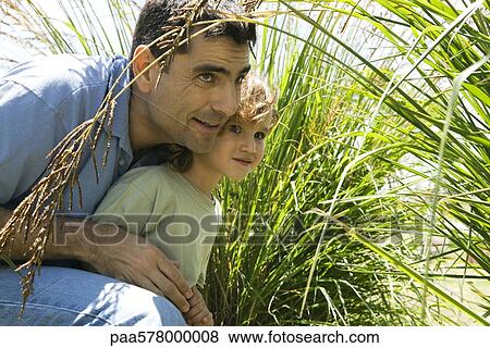 Father and son hiding in tall grass View Large Photo Image Stock Photo - Father and son hiding in tall grass. Fotosearch