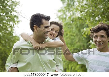 Stock Photo - Father and sons having fun together outdoors. Fotosearch