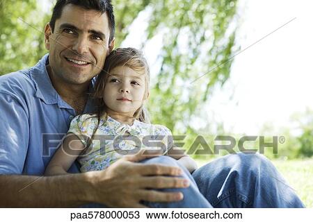Father holding young daughter on lap outdoors View Large Photo Image Stock Image - Father holding young daughter on lap outdoors. Fotosearch