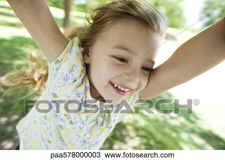Stock Image - Little girl being spun by arms outdoors. Fotosearch