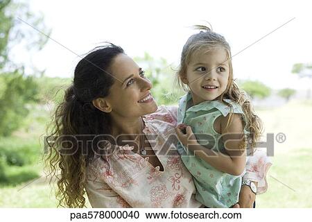 Mother holding young daughter outdoors View Large Photo Image Stock Image - Mother holding young daughter outdoors. Fotosearch
