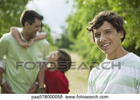 Teenage boy outdoors with father and younger brothers, portrait View Large Photo Image Stock Photo - Teenage boy outdoors with father and younger brothers, portrait. Fotosearch
