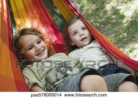 Picture - Young brother and sister lying in hammock together. Fotosearch