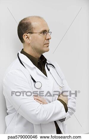 Doctor leaning against wall, arms folded, portrait View Large Photo Image Stock Photograph - Doctor leaning against wall, arms folded, portrait. Fotosearch