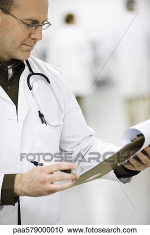 Doctor looking at medical chart View Large Photo Image Stock Image - Doctor looking at medical chart. Fotosearch