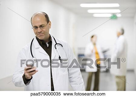 Doctor using cell phone View Large Photo Image Stock Photography - Doctor using cell phone. Fotosearch