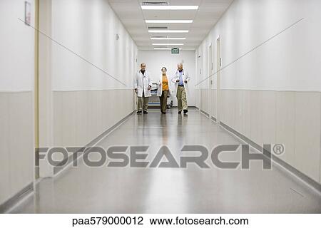 Stock Image - Doctors hurrying down hospital corridor. Fotosearch
