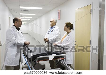 Doctors talking in hospital corridor View Large Photo Image Stock Photograph - Doctors talking in hospital corridor. Fotosearch