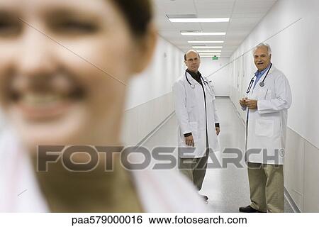 Doctors talking together in hospital corridor View Large Photo Image Stock Photograph - Doctors talking together in hospital corridor. Fotosearch