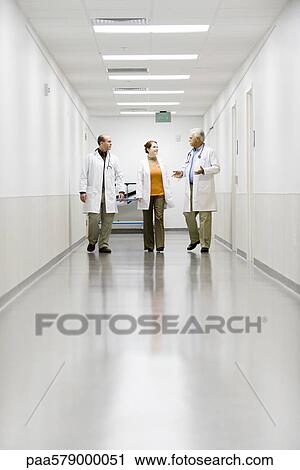 Doctors walking down hospital corridor View Large Photo Image Stock Image - Doctors walking down hospital corridor. Fotosearch