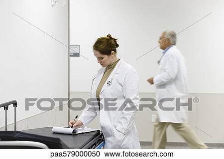 Female doctor looking at medical chart View Large Photo Image Stock Image - Female doctor looking at medical chart. Fotosearch
