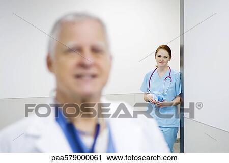Nurse leaning against wall looking with admiration at doctor View Large Photo Image Stock Image - Nurse leaning against wall looking with admiration at doctor. Fotosearch