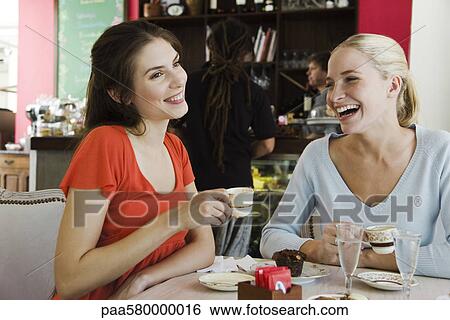 Stock Photograph - Female friends having coffee at cafe. Fotosearch
