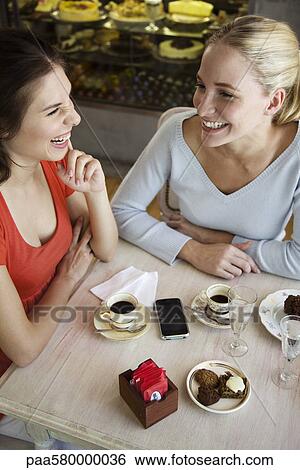 Female friends having coffee together at cafe View Large Photo Image Stock Photograph - Female friends having coffee together at cafe. Fotosearch
