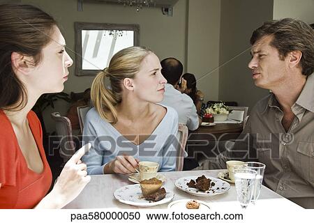 Stock Image - Friends having discussion at cafe. Fotosearch