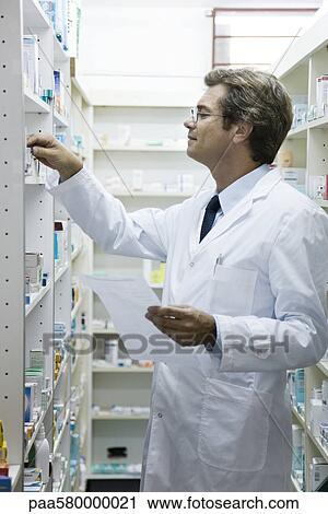 Stock Image - Pharmacist checking shelf for medication. Fotosearch
