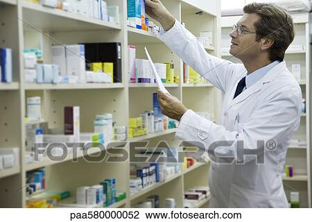 Stock Image - Pharmacist checking shelf for medication. Fotosearch