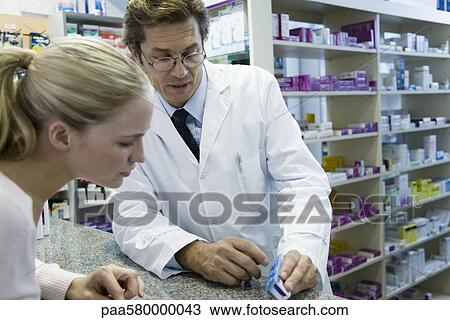 Stock Image - Pharmacist explaining prescription to customer. Fotosearch