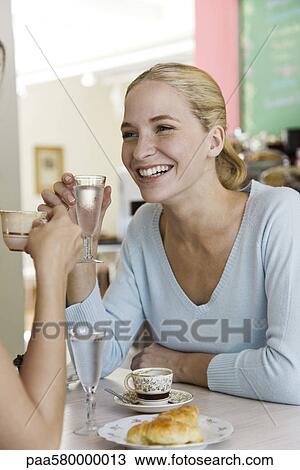 Young woman sitting with friend in cafe View Large Photo Image Stock Image - Young woman sitting with friend in cafe. Fotosearch