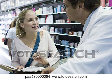 Picture - Young woman talking to pharmacist. Fotosearch