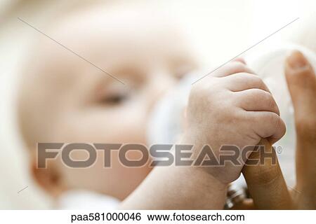 Baby drinking from bottle and holding mother's finger, close-up View Large Photo Image Stock Photograph - Baby drinking from bottle and holding mother's finger, close-up. Fotosearch