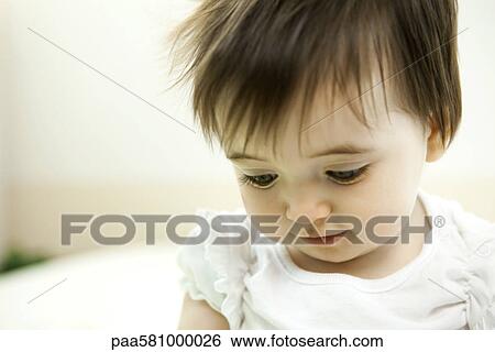 Stock Photograph - Baby girl looking down, portrait. Fotosearch