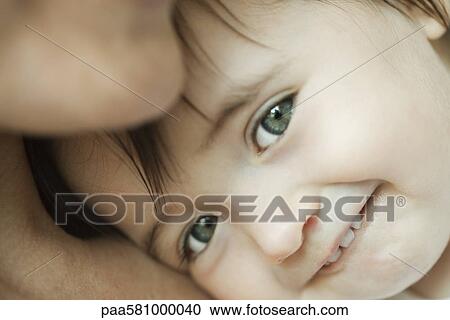 Stock Image - Baby leaning against mother's chest, portrait. Fotosearch