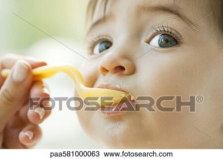 Infant being fed with a spoon View Large Photo Image Stock Image - Infant being fed with a spoon. Fotosearch
