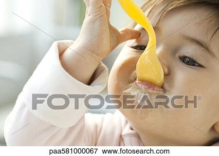 Infant eating with spoon View Large Photo Image Stock Photo - Infant eating with spoon. Fotosearch