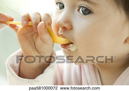 Infant learning to eat with a spoon View Large Photo Image Stock Image - Infant learning to eat with a spoon. Fotosearch