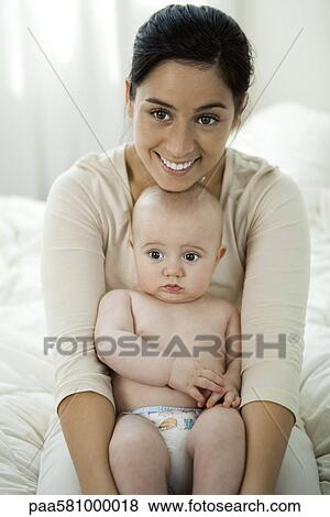 Stock Photo - Mother holding baby on lap, portrait. Fotosearch
