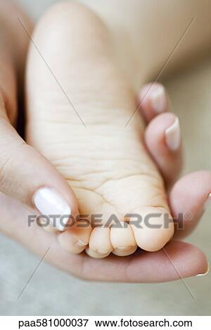 Woman's hand holding baby's foot View Large Photo Image Stock Photo - Woman's hand holding baby's foot. Fotosearch