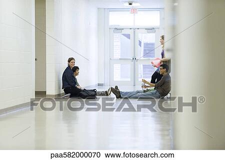 Stock Image - High school friends hanging out together in school corridor. Fotosearch