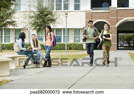 Stock Image - High school friends hanging out together on school campus. Fotosearch