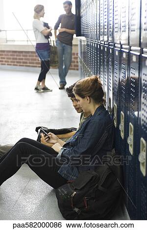 High school friends looking at cell phone together View Large Photo Image Stock Photograph - High school friends looking at cell phone together. Fotosearch