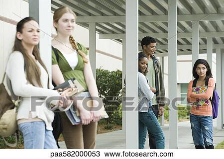 Stock Image - High school students waiting under covered walkway for bus after school. Fotosearch