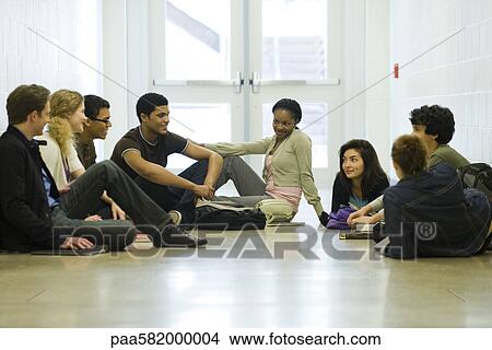Picture - Students hanging out together, sitting on school corridor floor. Fotosearch