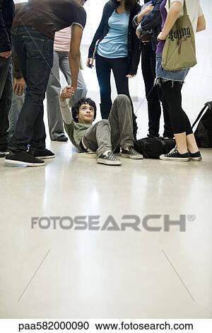 Teenage boy being helped up off of floor by friend View Large Photo Image Stock Image - Teenage boy being helped up off of floor by friend. Fotosearch