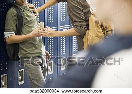 Picture - Teenage boy bullying classmate and stealing his money. Fotosearch