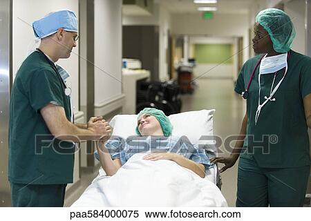 Doctor reassuring patient lying on hospital gurney View Large Photo Image Stock Photography - Doctor reassuring patient lying on hospital gurney. Fotosearch