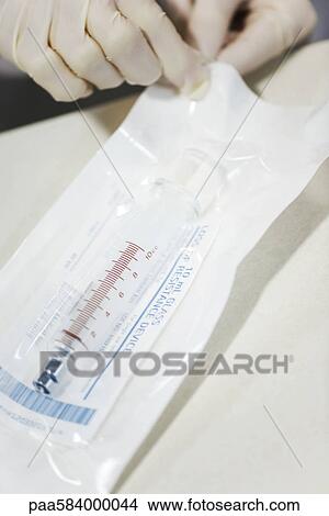 Healthcare worker opening sterile package containing medical syringe View Large Photo Image Picture - Healthcare worker opening sterile package containing medical syringe. Fotosearch