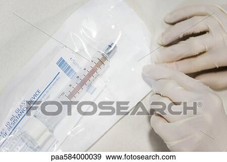 Healthcare worker opening sterile package containing medical syringe View Large Photo Image Stock Photo - Healthcare worker opening sterile package containing medical syringe. Fotosearch