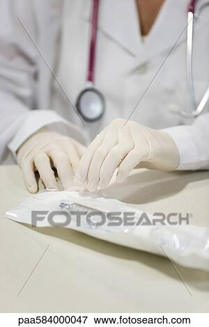 Healthcare worker opening sterile package containing medical supplies View Large Photo Image Stock Photo - Healthcare worker opening sterile package containing medical supplies. Fotosearch