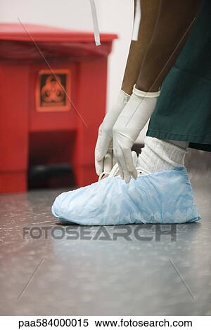 Healthcare worker putting on disposable shoe covers View Large Photo Image Stock Photography - Healthcare worker putting on disposable shoe covers. Fotosearch