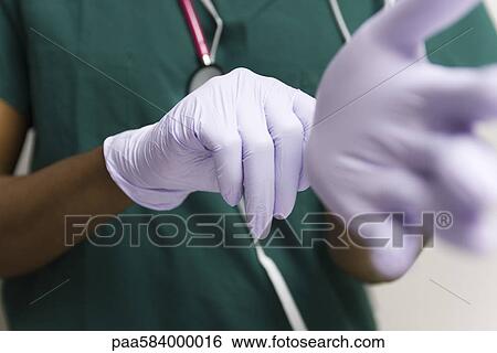 Healthcare worker putting on latex gloves View Large Photo Image Stock Photograph - Healthcare worker putting on latex gloves. Fotosearch