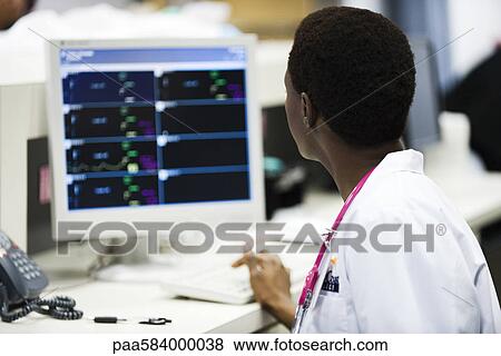 Healthcare worker watching monitor at nurse's station View Large Photo Image Stock Photo - Healthcare worker watching monitor at nurse's station. Fotosearch