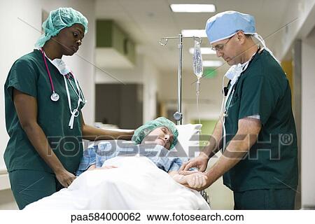 Healthcare workers treating patient on hospital gurney View Large Photo Image Stock Image - Healthcare workers treating patient on hospital gurney. Fotosearch