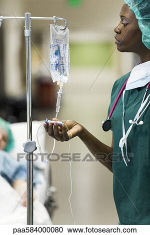 Nurse checking flow of saline from patient's IV drip View Large Photo Image Stock Image - Nurse checking flow of saline from patient's IV drip. Fotosearch